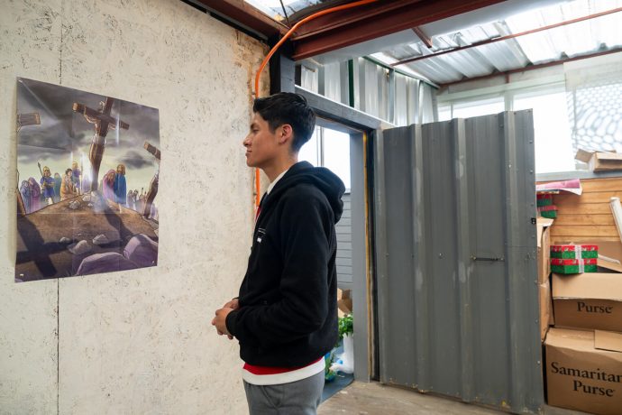 John looks at poster of crucifixion