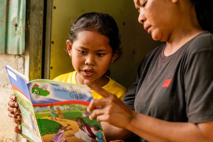 Cambodian girl reads discipleship lesson to her mother