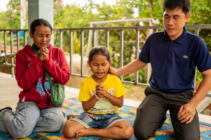 Pastor Kosal and Tola pray at a community event in Cambodia