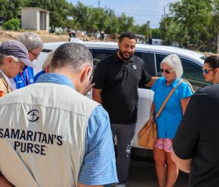 Samaritan's Purse group praying over new vehicle for Texas flood survivor.
