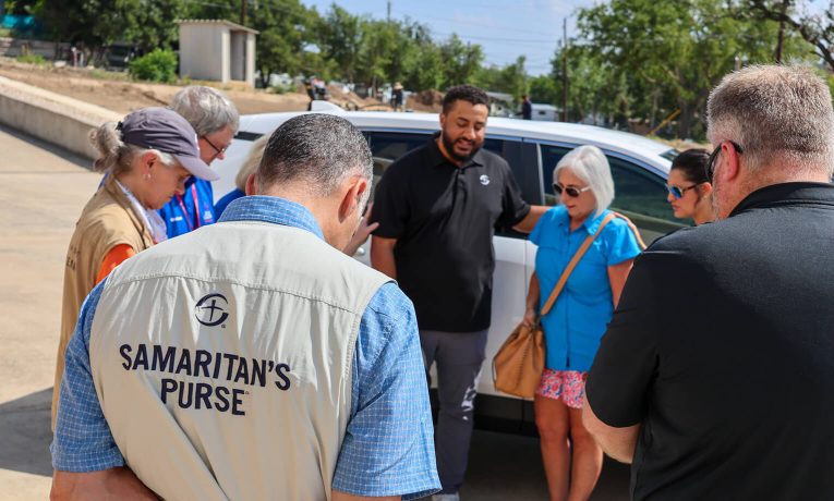 Samaritan's Purse group praying over new vehicle for Texas flood survivor.