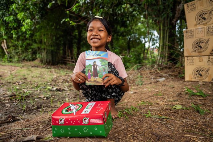 Shoebox recipient beams as she displays her Gospel booklet