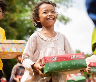 Excited boy and girl hold shoebox gifts