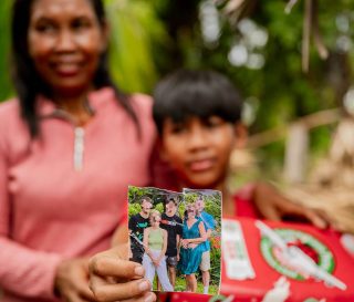 Together with his mother, a boy holds out the photo of the family that packed his shoebox gift