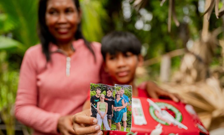 Together with his mother, a boy holds out the photo of the family that packed his shoebox gift