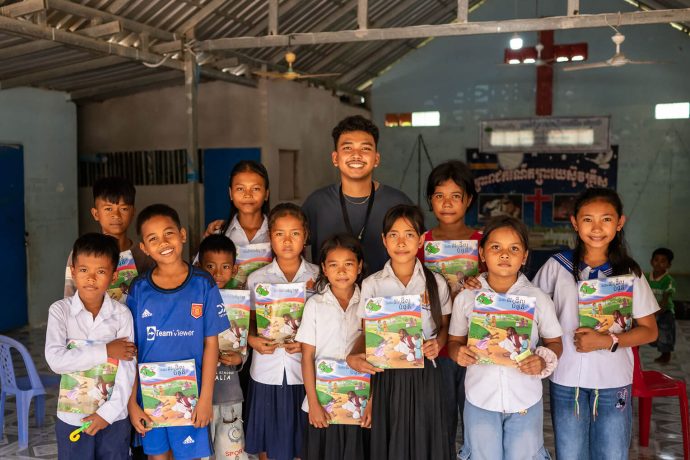 Phirun's class of The Greatest Journey pose with their student workbooks