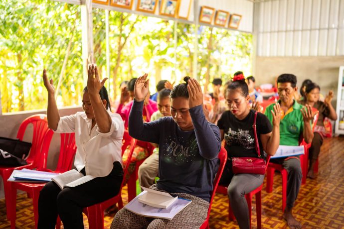 Cambodian congregation worships with hands raised