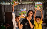 Samnang and two of her students joyfully hold up The Greatest Journey workbooks