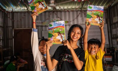 Samnang and two of her students joyfully hold up The Greatest Journey workbooks
