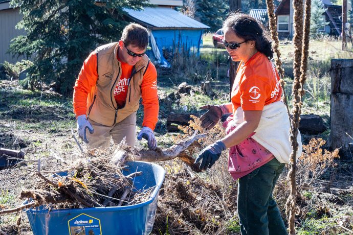 Volunteers fill wheelbarrow with debris from flood