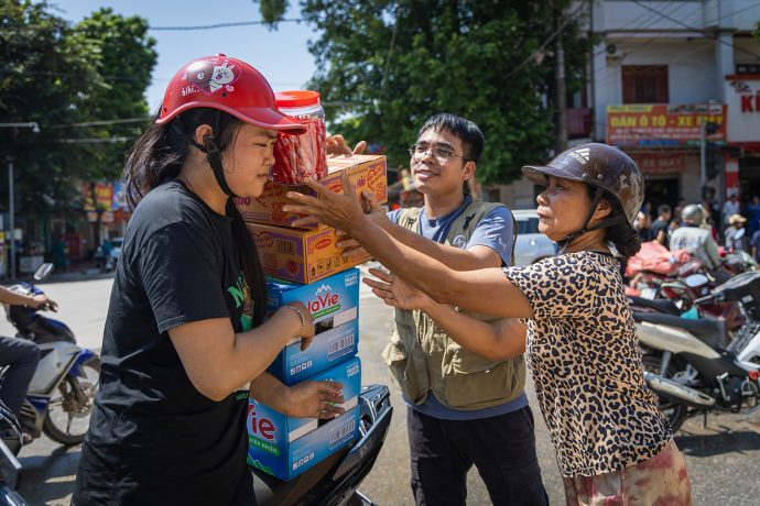 Thuyet, left, stacks food and water she received at a Samaritan's Purse distribution onto her motorcycle to bring back home to her family. 