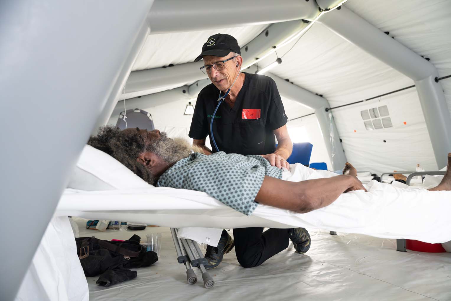 Dr. Joe Lamb, a longtime DART physician with Samaritan's Purse, encourages an elderly patient brought in the first day of operation at the field hospital.