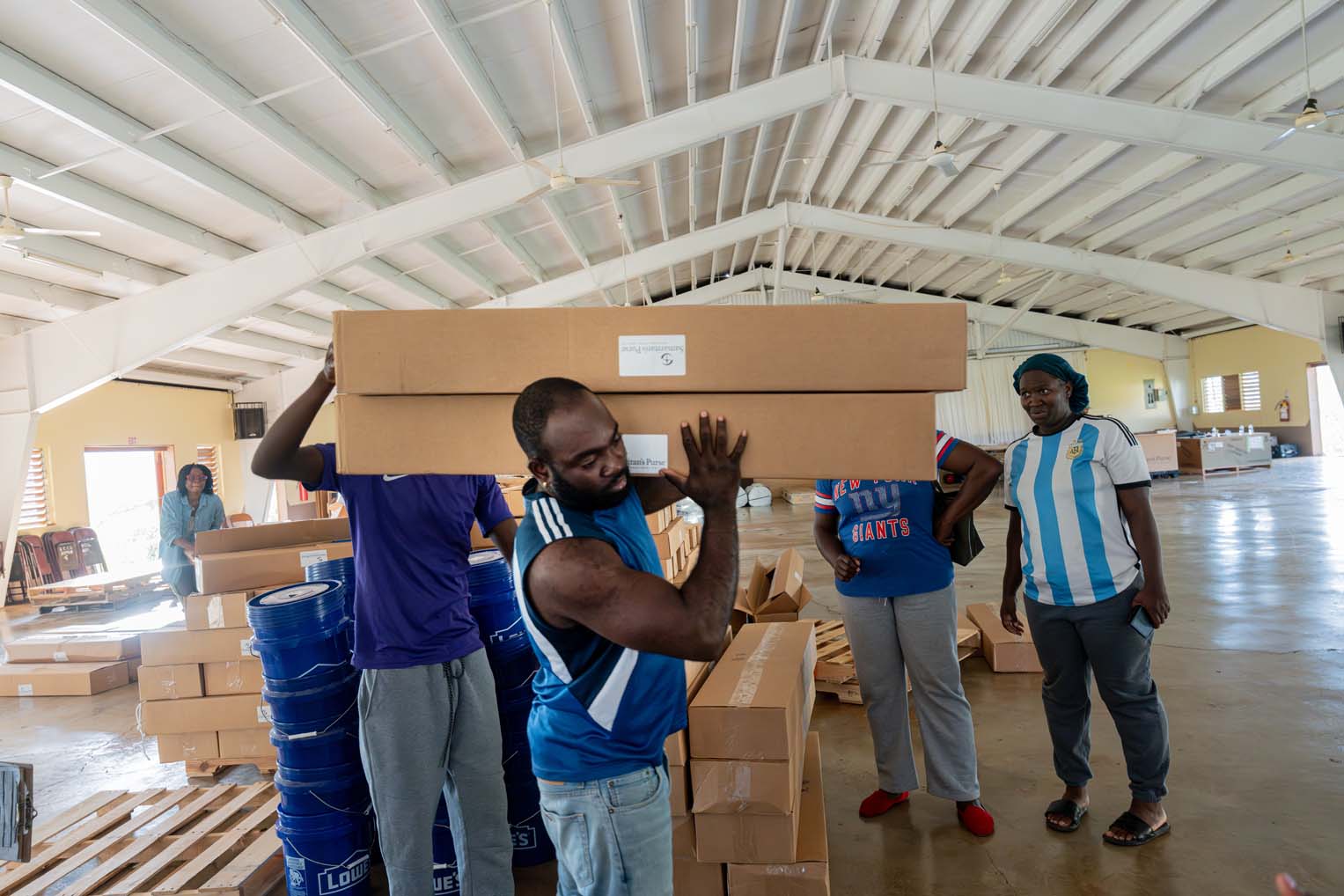 Group of Jamaican volunteers lifting boxes of Samaritan’s Purse relief supplies inside a warehouse after Hurricane Melissa.