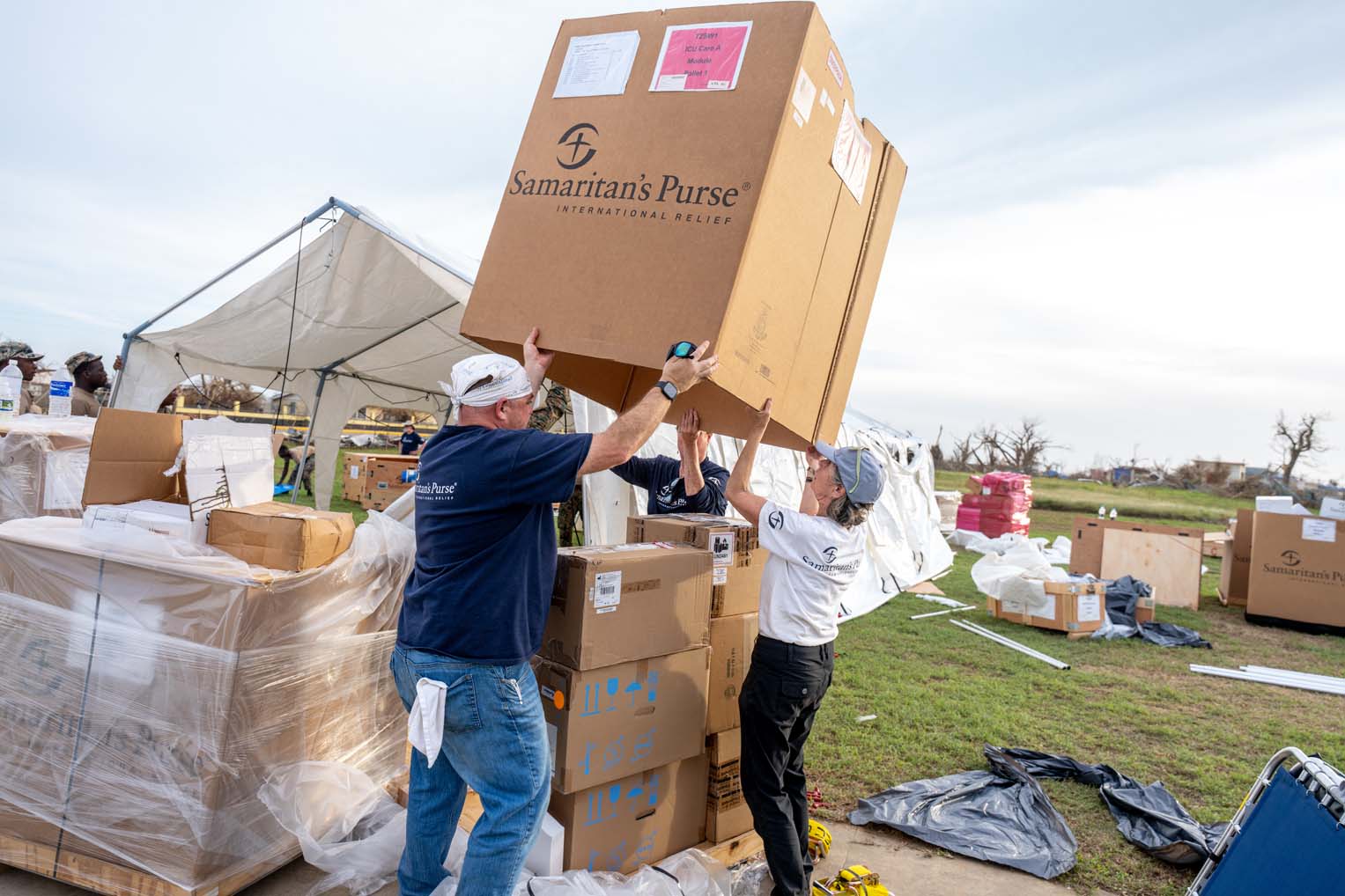 Samaritan’s Purse workers lifting large boxes of relief supplies at a hurricane response site in Jamaica.