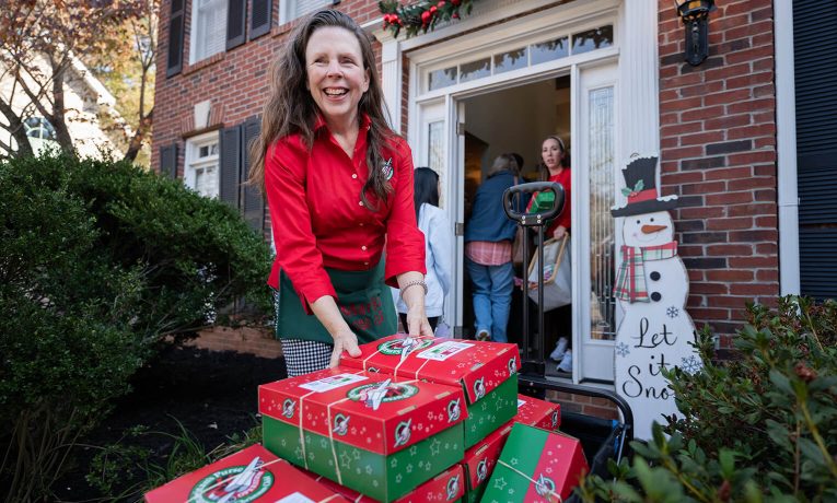 Marika at her front door with shoeboxes