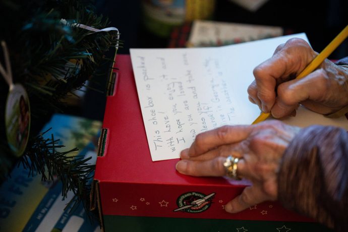 woman writes note to include in shoebox gift