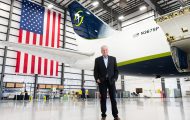 Samaritan's Purse President Franklin Graham stands inside a large aircraft hangar in front of a Samaritan’s Purse cargo plane, with a large American flag hanging behind the aircraft’s tail.