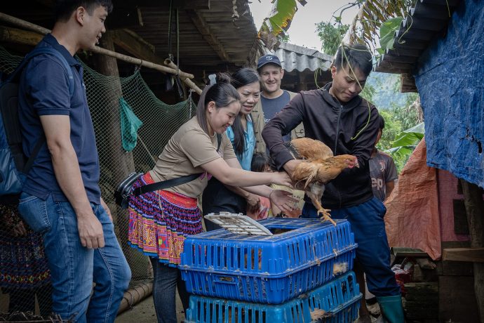 Lang, right, unloads his 40 chickens in a coop he built near his house. Both the poultry and the supplies to build the coop were provided to the young father by Samaritan's Purse.