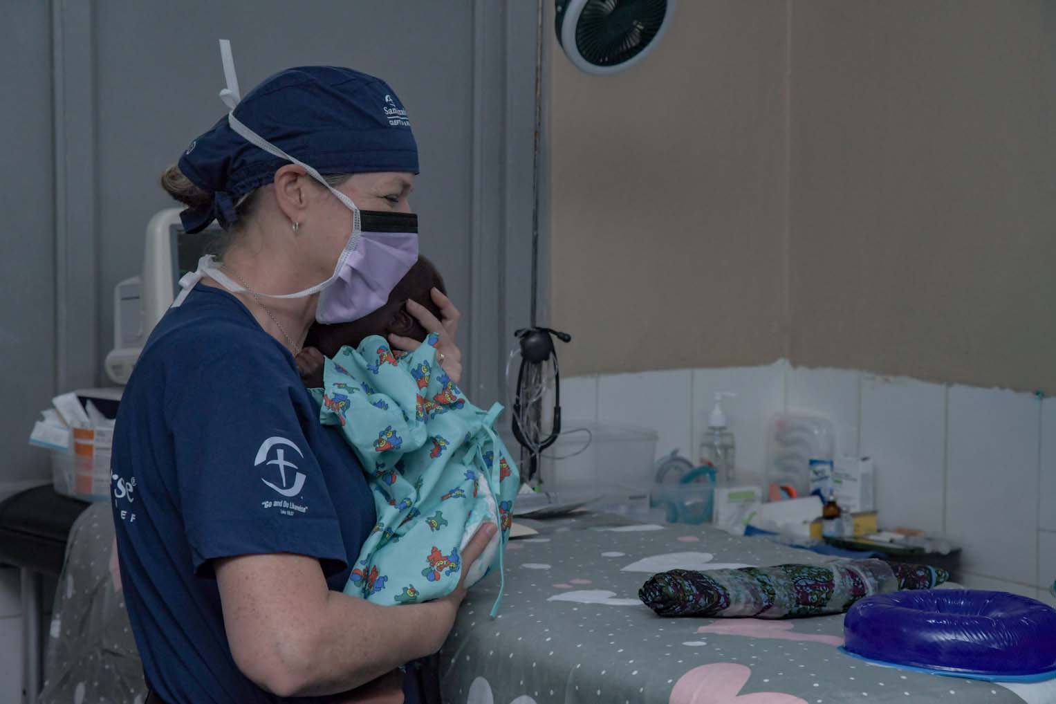 A member of the surgical team gently carries Adeni, still groggy from anesthesia, to recover in his mother's arms.