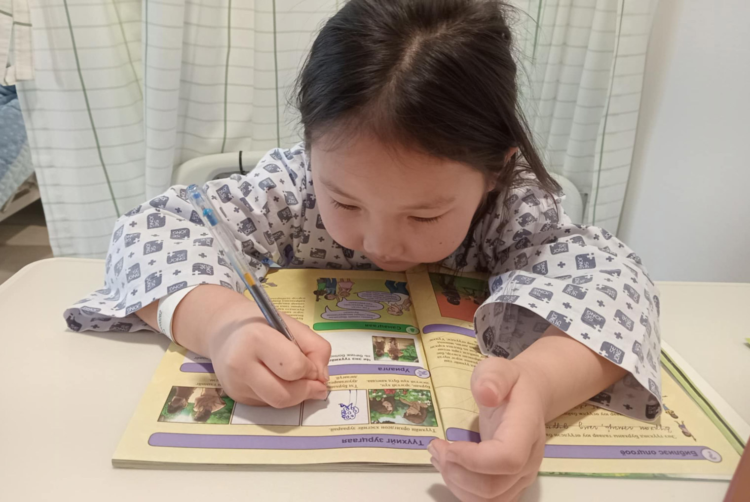 Anujin draws a picture of a Bible story illustrated in The Greatest Journey booklet.