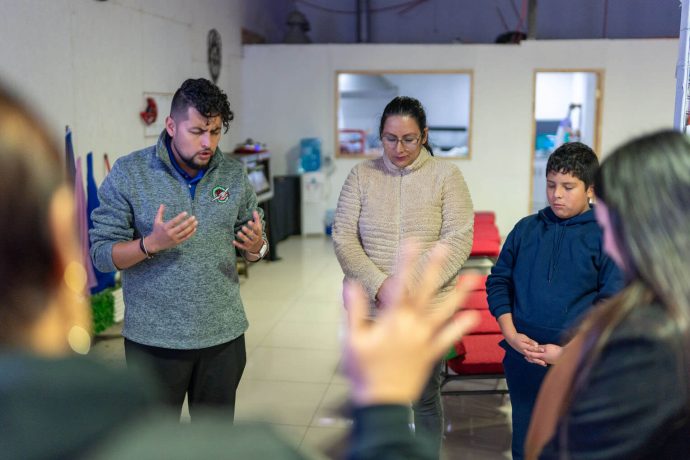 Operation Christmas Child representative prays with The Greatest Journey student and his mother