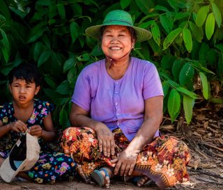 Smiling woman sitting on ground with child.