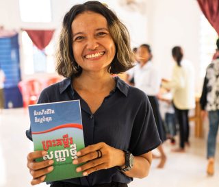 Cambodian volunteer with Cambodian Bible given to graduates of The Greatest Journey