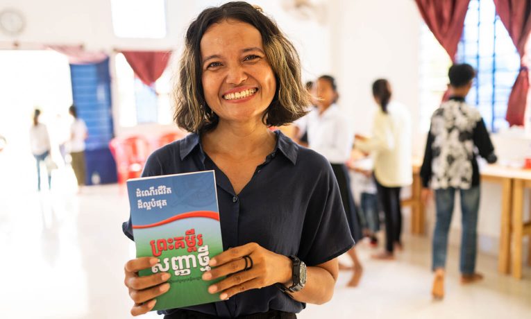 Cambodian volunteer with Cambodian Bible given to graduates of The Greatest Journey