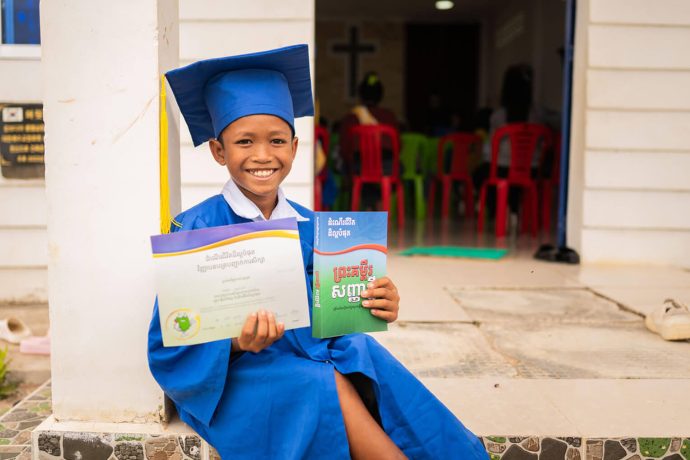 Boy graduating from The Greatest Journey displays his certificate and Bible