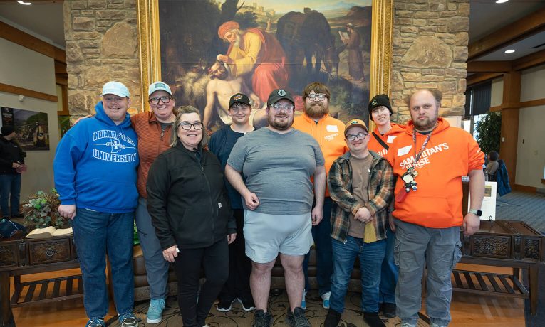 disabled adults in front of painting of the Good Samaritan