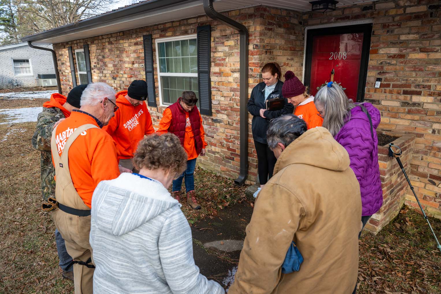 Volunteers pray with homeowners and provide a Bible signed by the team.