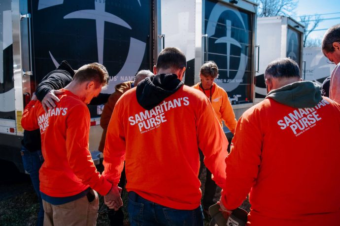 Volunteers circle to pray in front of Samaritan's Purse trucks
