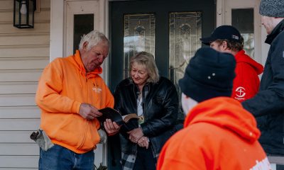 Volunteers open Bible with homeowner