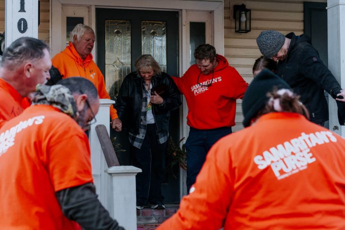 Volunteers pray with homeowner