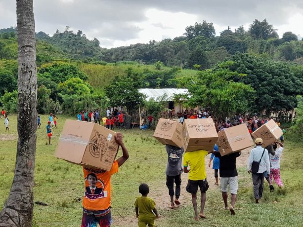 parents carry cartons of shoeboxes to waiting children