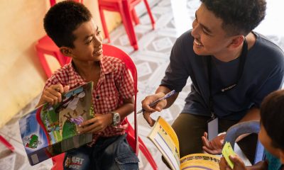 Sann interacts with a student of The Greatest Journey over his workbook