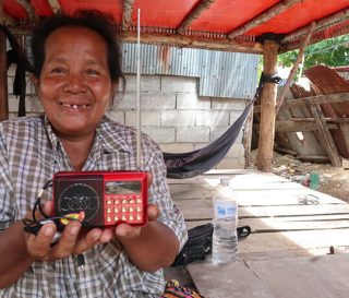 Long smiles holding the audio Bible that is helping her grow in her new faith in Jesus Christ.
