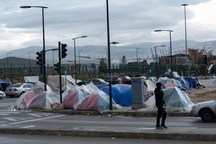 makeshift tent camp on the side of a street with hills in background