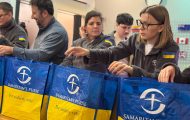 Samaritan's Purse staff pack emergency winter kits into bags labeled with 'God loves you' in Ukrainian