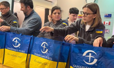 Samaritan's Purse staff pack emergency winter kits into bags labeled with 'God loves you' in Ukrainian