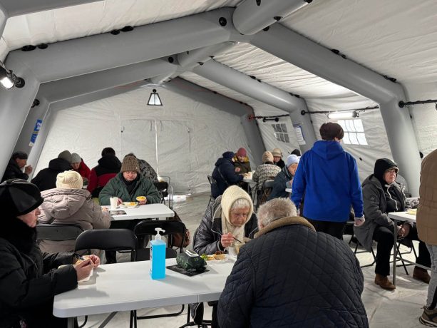 People sit at tables inside Samaritan's Purse warming center