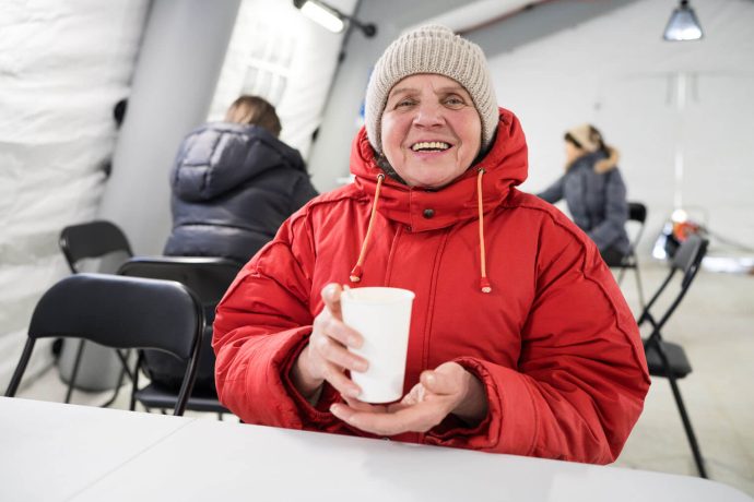 Bundled in a red jacket, Anna smiles while holding a warm drink