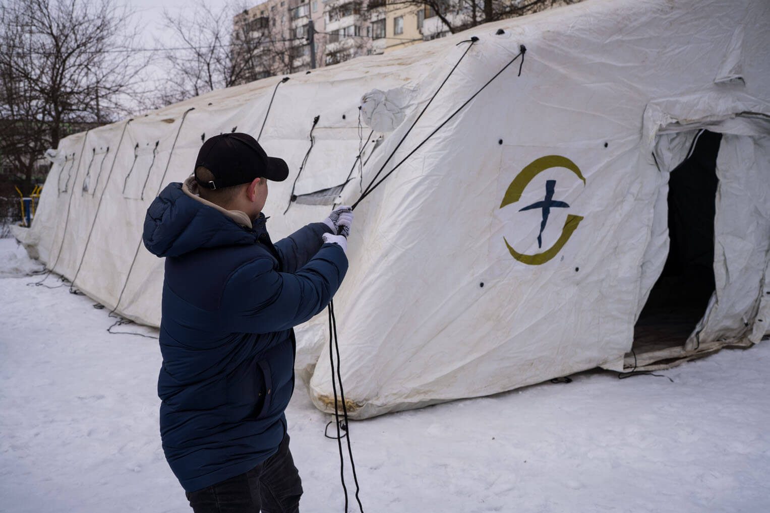 Person works to secure Samaritan's Purse tent from the outside