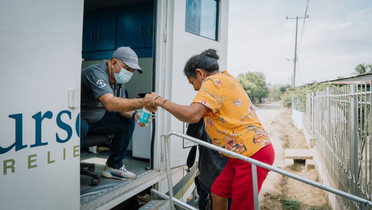 A Samaritan's Purse medical staffer helps Amira onto the mobile medical unit for her consultation where she received medicine and a comprehensive health checkup.