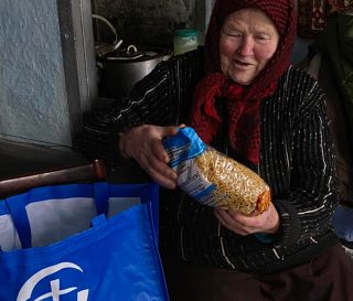 Hanna smiles as she opens a bag of groceries from Samaritan's Purse