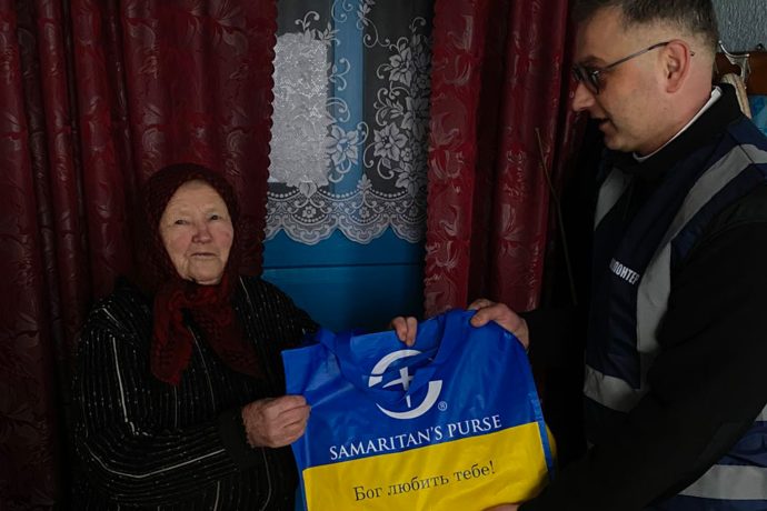 church partner hands Hanna a bag of groceries from Samaritan's Purse