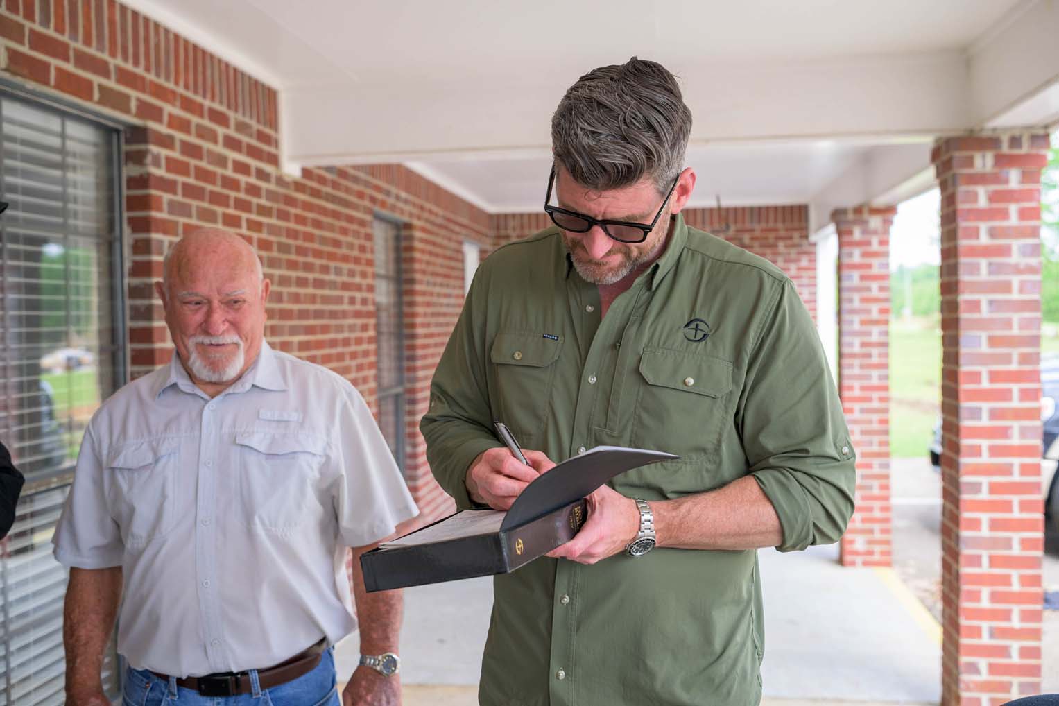 Edward Graham signs a special Billy Graham Training Center Bible to be gifted to Coaltown Baptist Church. The congregation was enjoying midweek services when a tornado ripped the roof from the building.