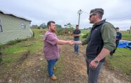 Edward Graham greets a Mississippi homeowner in front of his home. They shake hands.