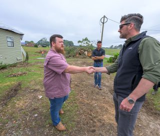 Edward Graham greets a Mississippi homeowner in front of his home. They shake hands.