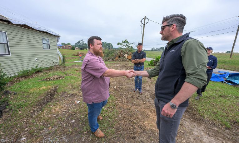 Edward Graham greets a Mississippi homeowner in front of his home. They shake hands.